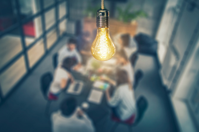 Image of a bright lightbulb above a team hard at work.