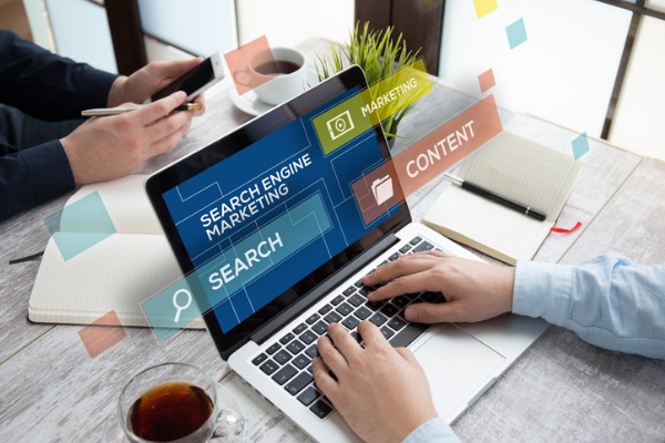 An image showing a laptop with “Search Engine Marketing” on it, along with a search bar and the words “Content” and “Marketing.”