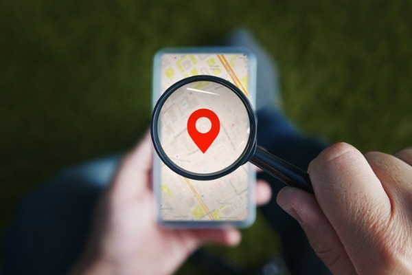 An image showing a magnifying glass over a smartphone with the location symbol.