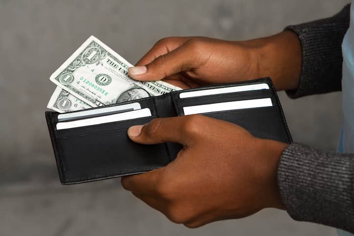 An image showing dollar bills being pulled out of a wallet.
