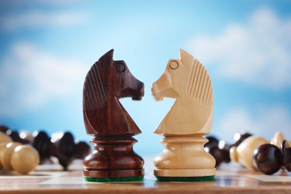 Two knights face each other on a chess table