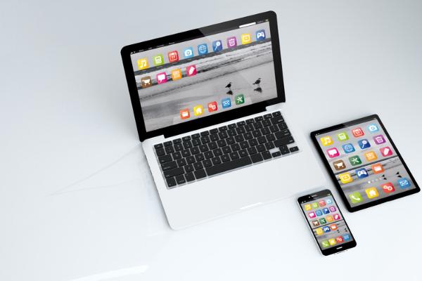 A laptop, tablet and phone rest on a white surface