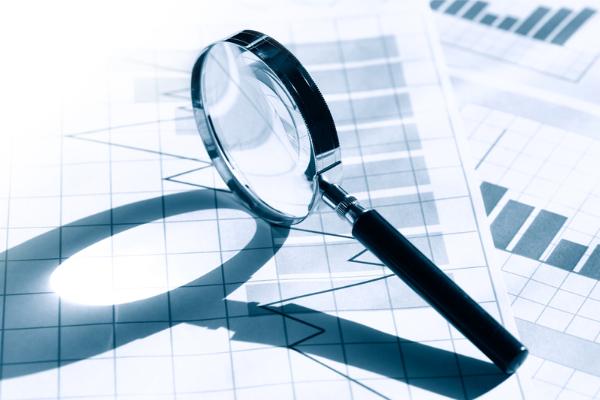 A magnifying glass rests upon a pile of corporate papers.