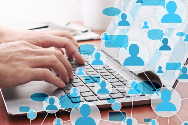 An image showing someone at a laptop with social media icons for comments, likes, and shares representing their social media strategy. 