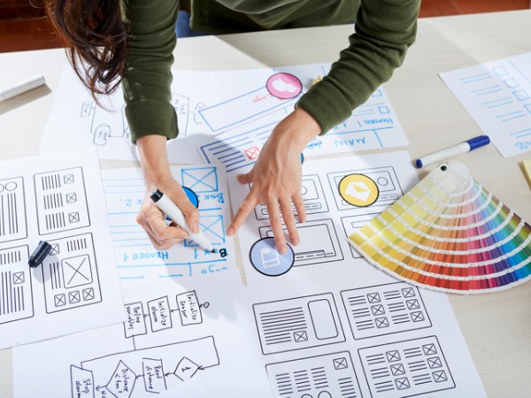 A bird’s-eye-view image showing a person working on various sketches for new logo designs. 