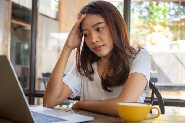 A woman looks at a computer in confusion