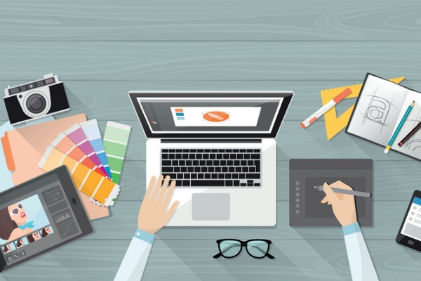 Person using color palettes, notebook and laptop to create custom graphic design