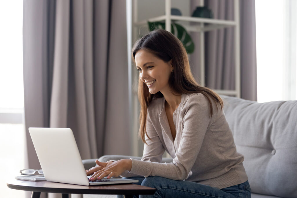 A woman sits on the couch and uses her laptop to optimize for local SEO ranking factors