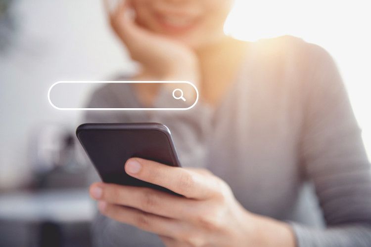 A woman uses a mobile phone to search the web, which is one of the local SEO ranking factors.