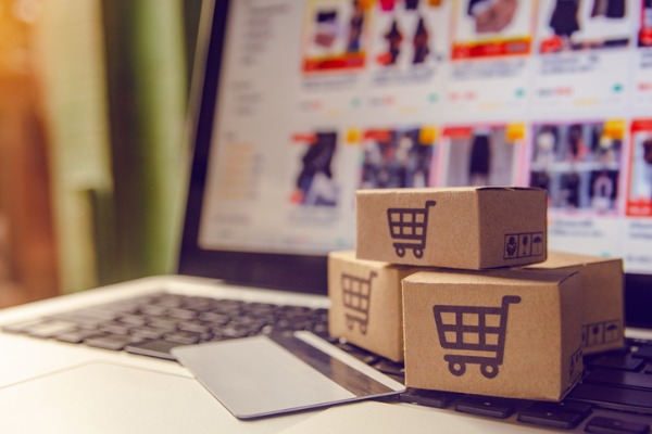 An image showing boxes with the online shopping cart logo next to a computer. 