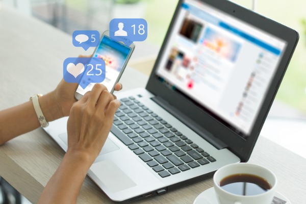 An image of a person on Facebook on their smart phone and on their laptop. 