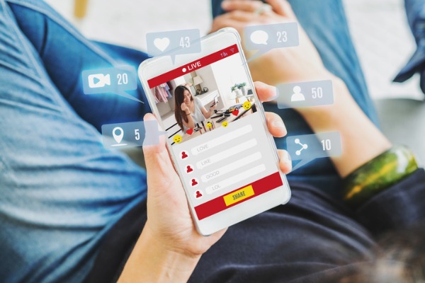 An image showing someone watching a live video surrounded by social media engagement icons. 