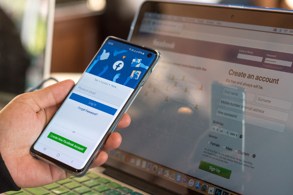 An image showing Facebook on a mobile device next to a laptop with Facebook open. 