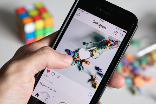 An image showing someone liking a photo on Instagram on their phone. 